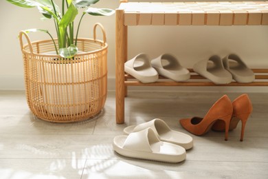 Many pairs of slippers and other shoes in entryway at home