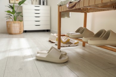 Photo of Many pairs of slippers and other shoes in entryway at home