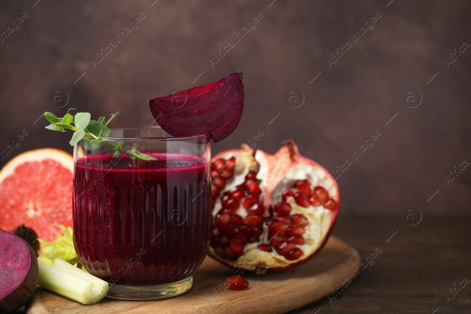 Photo of Tasty beetroot smoothie in glass, fresh vegetables and fruits on wooden table, closeup with space for text. Vegan drink