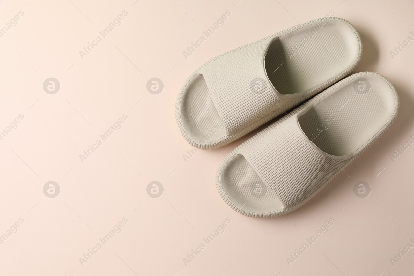 Photo of Pair of rubber slippers on beige background, top view. Space for text