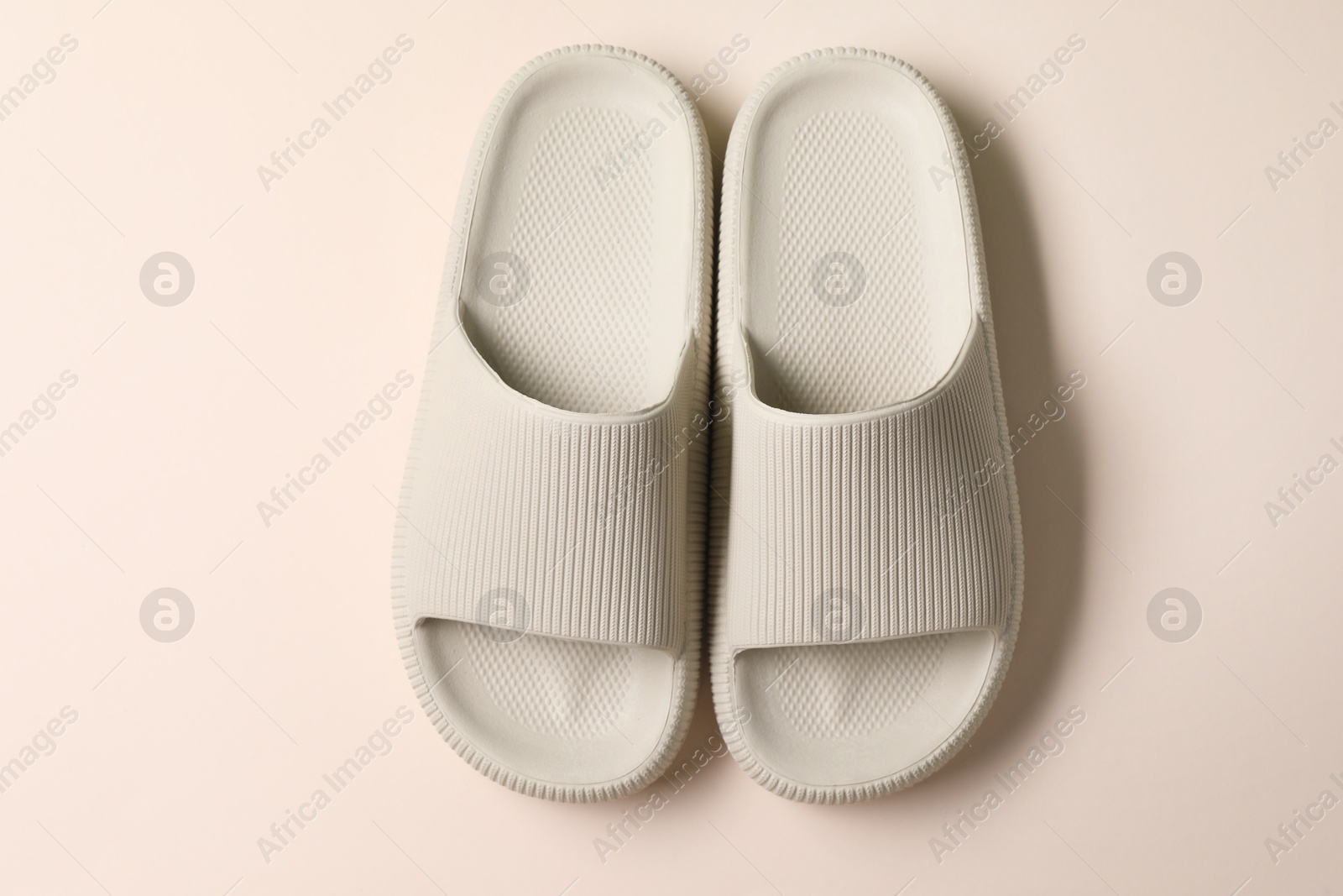 Photo of Pair of rubber slippers on beige background, top view