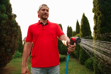 Photo of Man watering lawn with hose in backyard, selective focus