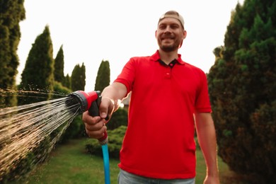 Photo of Man watering lawn with hose in backyard, selective focus