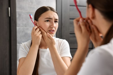 Photo of Young woman with toothbrush suffering from toothache in bathroom