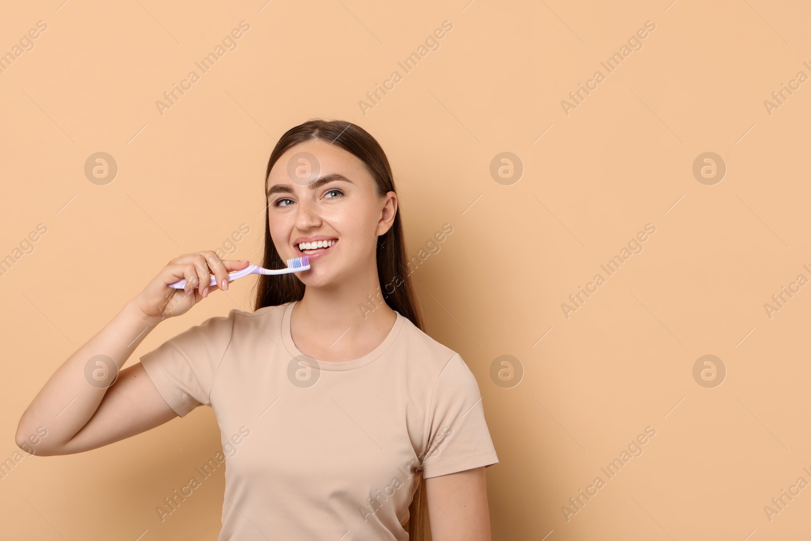 Photo of Beautiful woman brushing her teeth on beige background, space for text