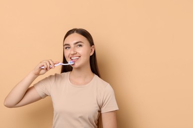 Photo of Beautiful woman brushing her teeth on beige background, space for text