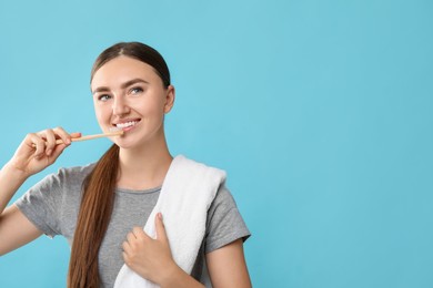 Photo of Beautiful woman brushing her teeth on light blue background, space for text