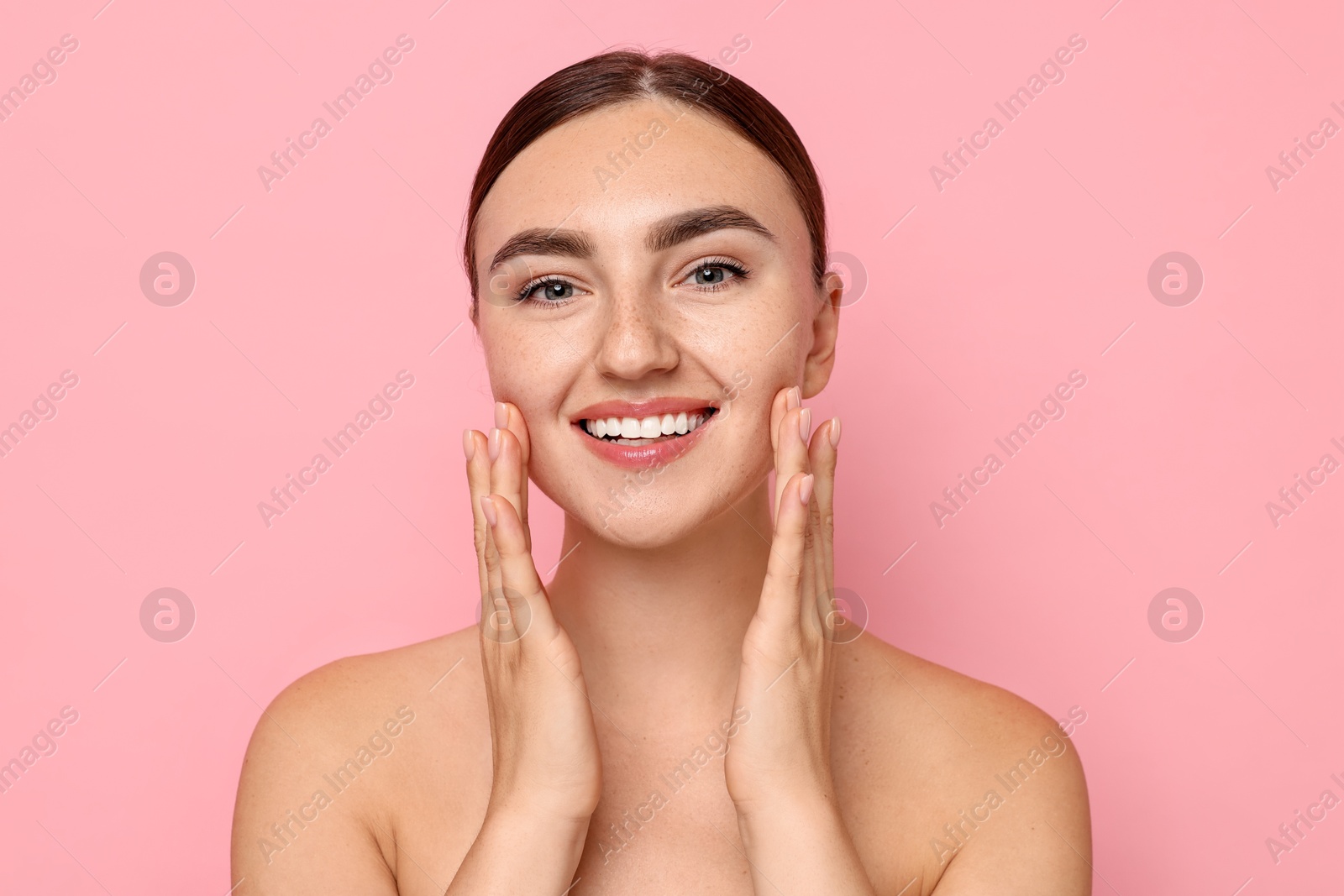 Photo of Face massage. Beautiful young woman with healthy skin on pink background