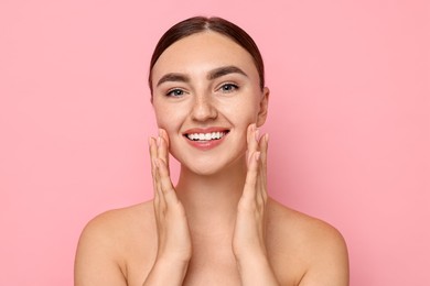 Photo of Face massage. Beautiful young woman with healthy skin on pink background