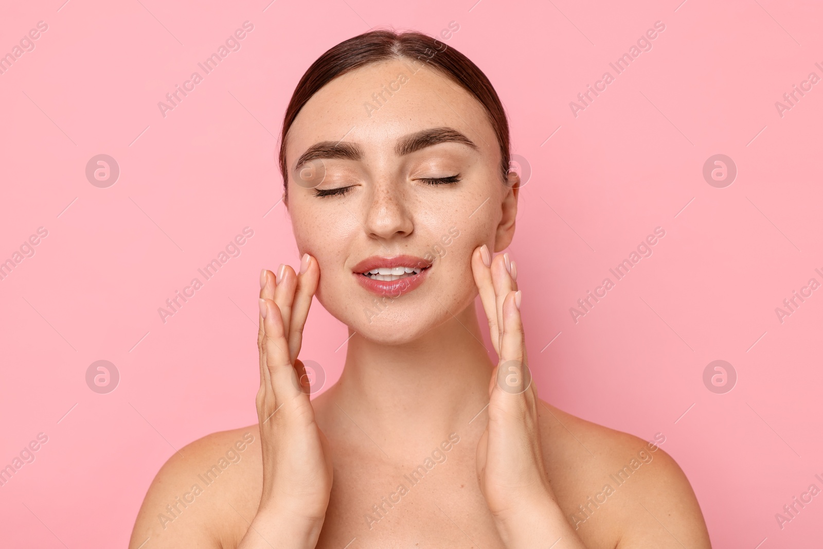 Photo of Face massage. Beautiful young woman with healthy skin on pink background