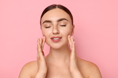 Face massage. Beautiful young woman with healthy skin on pink background