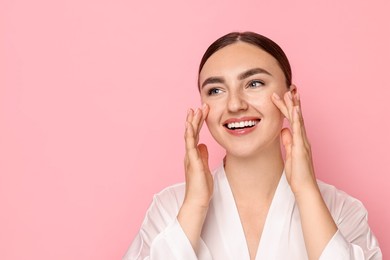 Photo of Face massage. Beautiful young woman with healthy skin on pink background, space for text