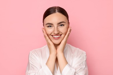 Photo of Face massage. Beautiful young woman with healthy skin on pink background