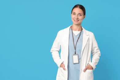 Photo of Nurse in medical uniform with badge on light blue background, space for text