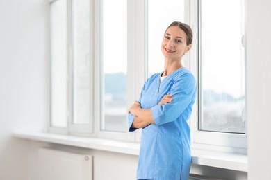 Photo of Nurse in medical uniform near window indoors