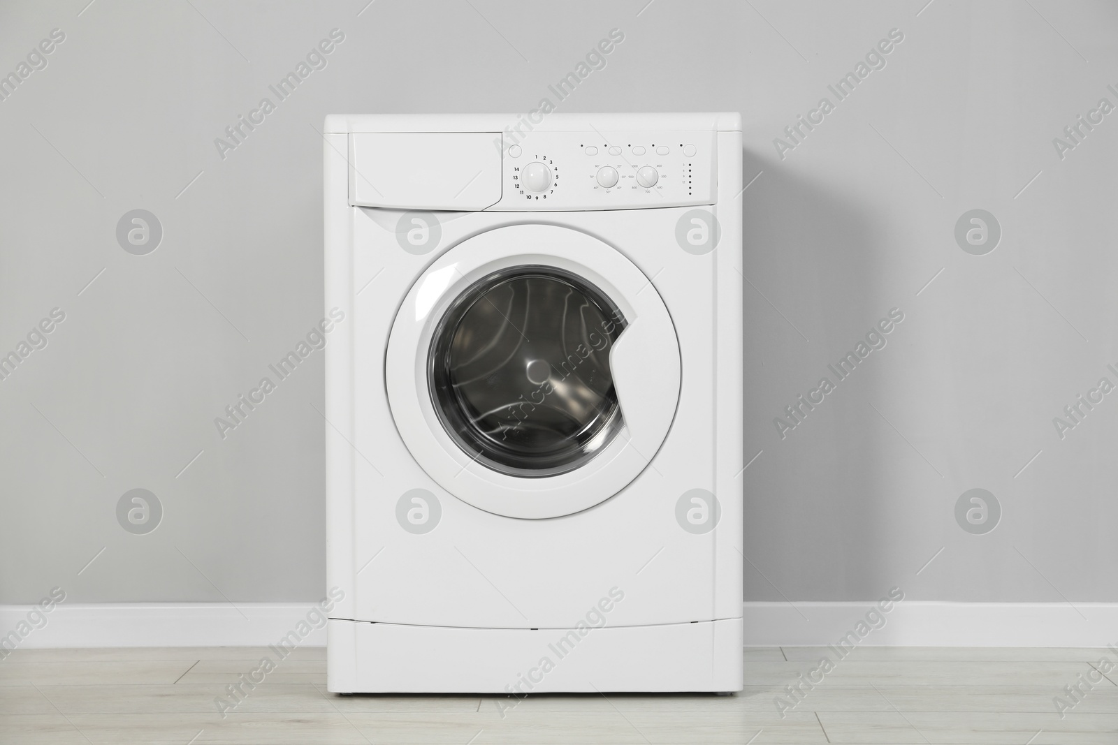 Photo of One washing machine near grey wall indoors