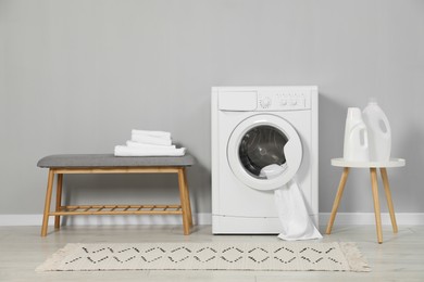 Photo of Washing machine, towels and detergents near grey wall