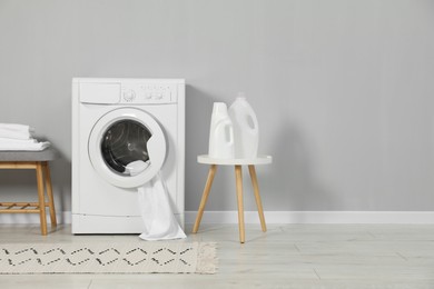 Photo of Washing machine, towels and detergents near grey wall, space for text