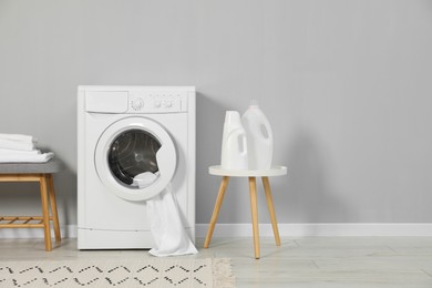 Photo of Washing machine, towels and detergents near grey wall, space for text