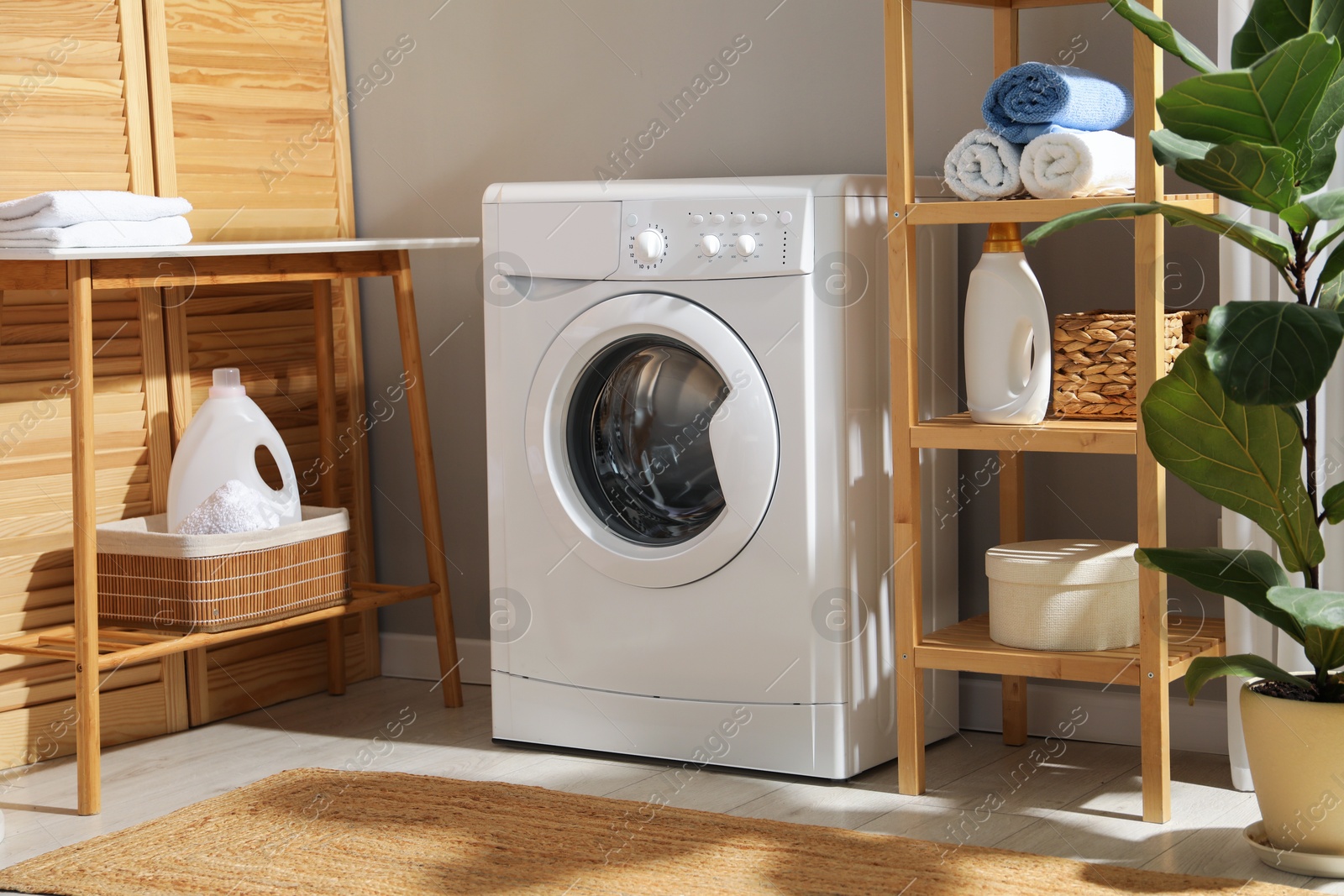 Photo of Washing machine, towels and detergents in laundry room