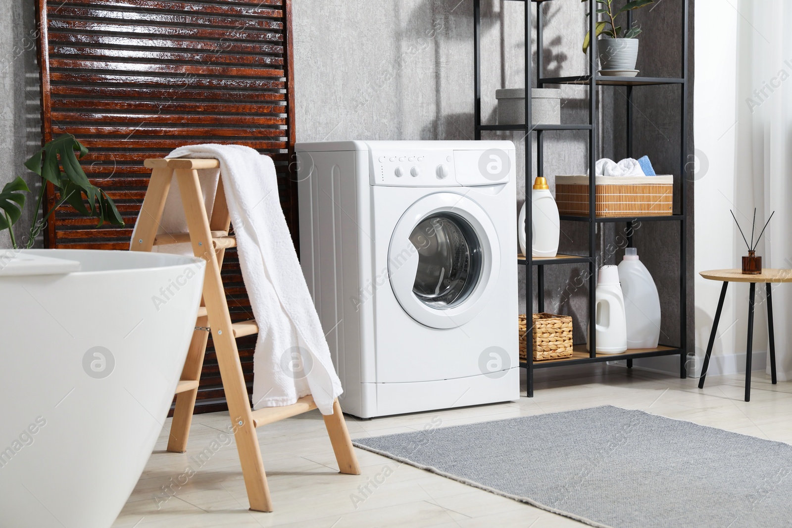 Photo of Washing machine, towels and detergents in bathroom