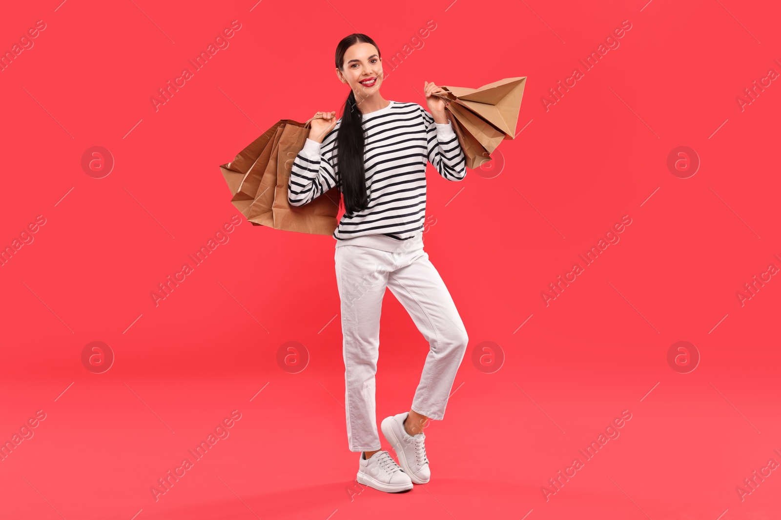 Photo of Smiling woman with shopping bags on red background