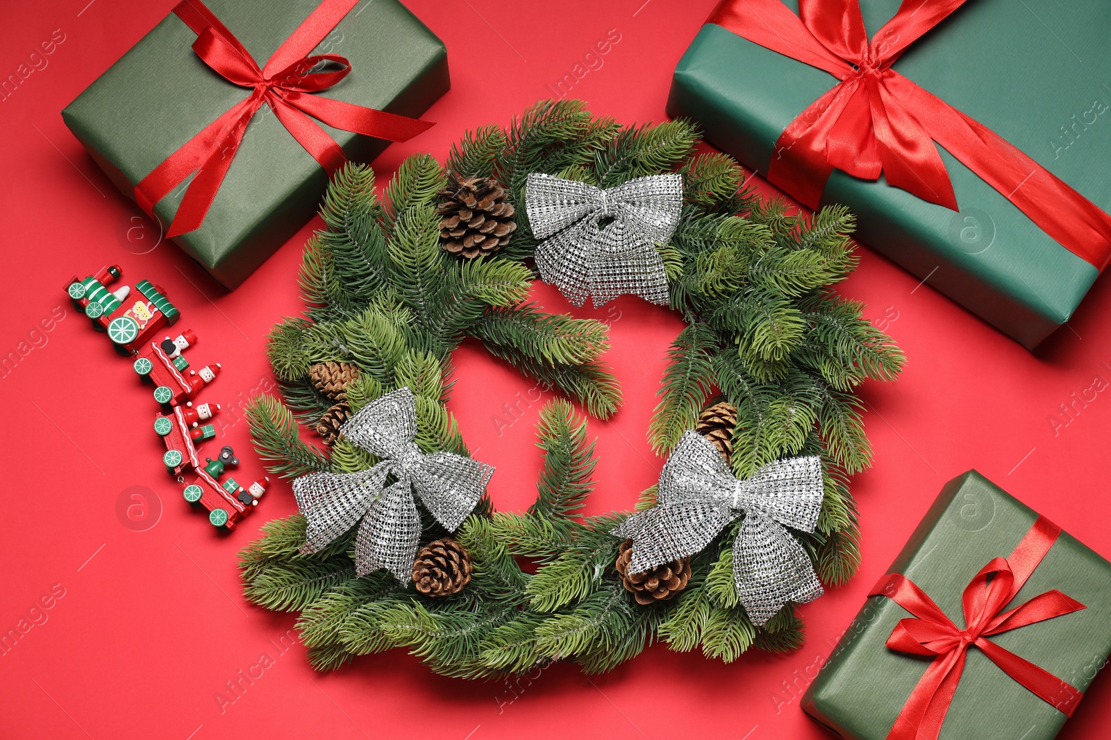 Photo of Christmas composition with festive decor on red background, flat lay