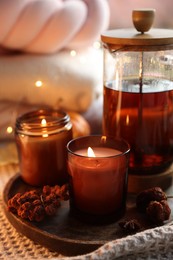 Photo of Burning candles, freshly brewed tea and autumn decor on fabric, closeup