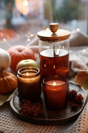 Photo of Burning candles, freshly brewed tea and autumn decor on fabric