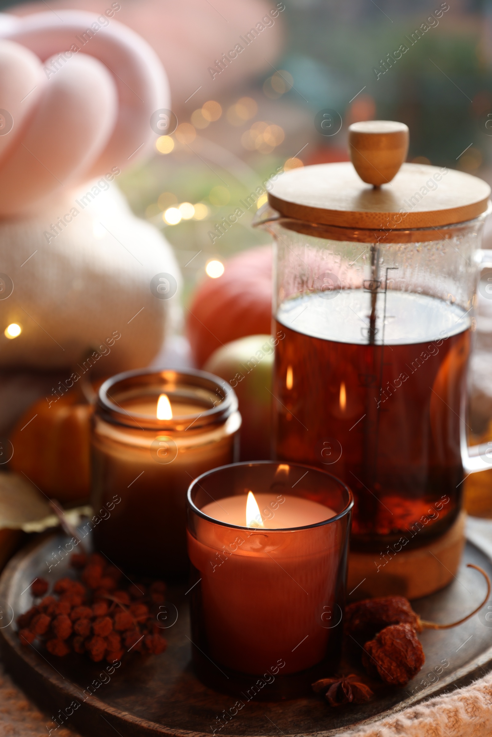 Photo of Burning candles, freshly brewed tea and autumn decor on fabric, closeup