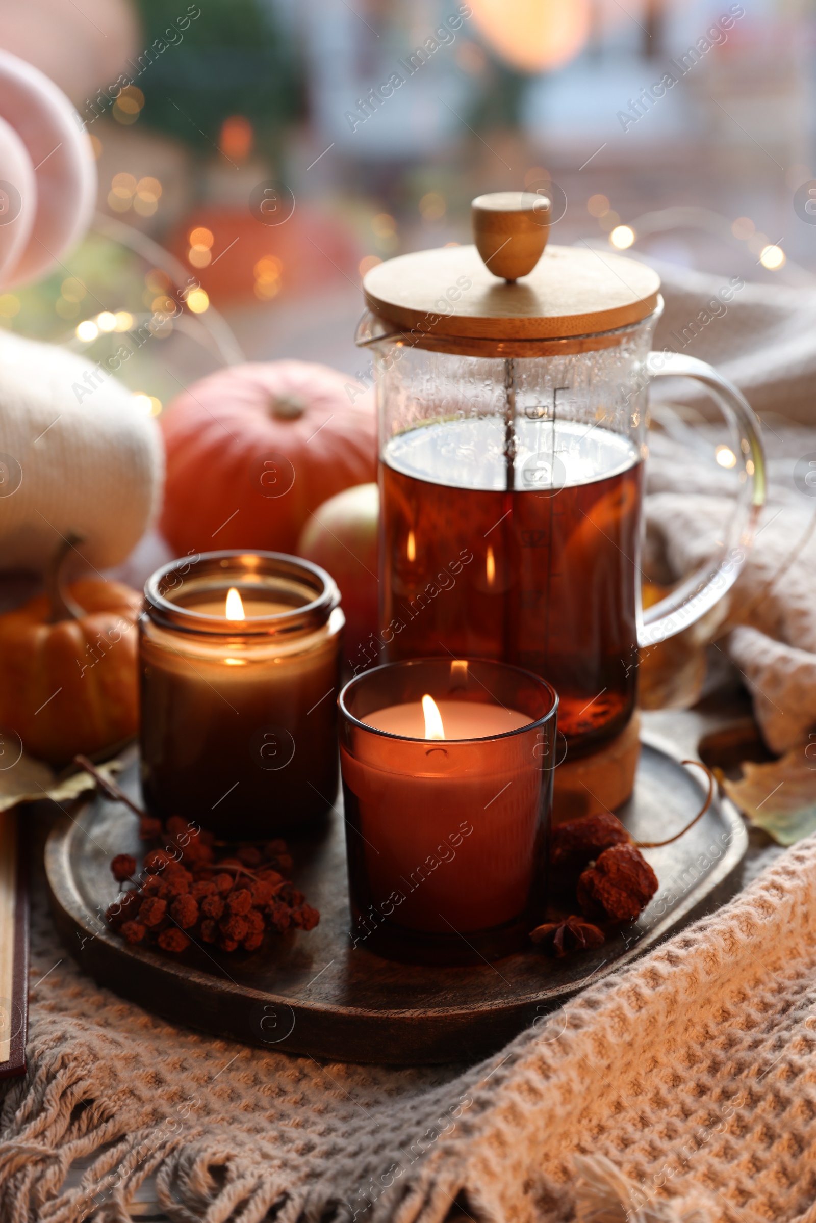 Photo of Burning candles, freshly brewed tea and autumn decor on fabric