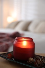 Photo of Burning candle and dry flowers on wooden table indoors, closeup. Autumn atmosphere