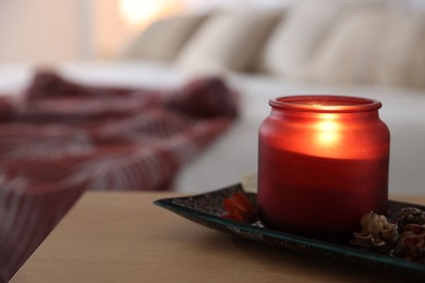 Photo of Burning candle and dry flowers on wooden table indoors, closeup. Autumn atmosphere