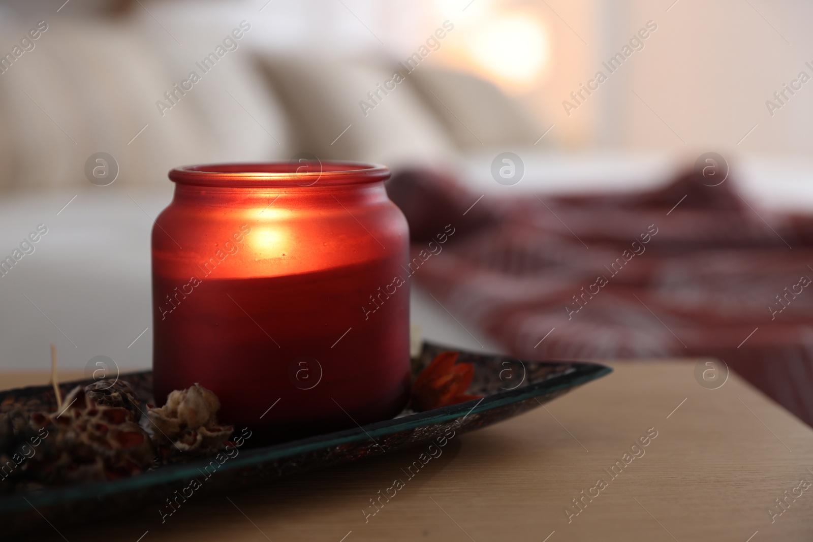 Photo of Burning candle and dry flowers on wooden table indoors, closeup. Autumn atmosphere