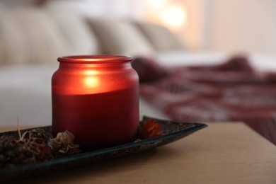 Photo of Burning candle and dry flowers on wooden table indoors, closeup. Autumn atmosphere