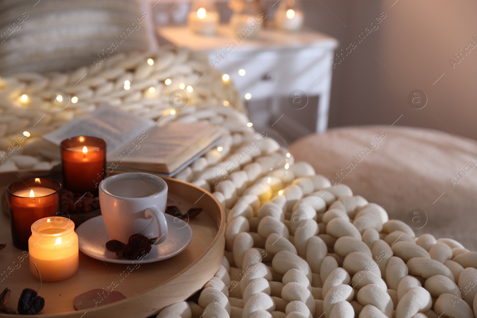 Photo of Burning candles, lights, coffee and decor on bed indoors. Autumn atmosphere