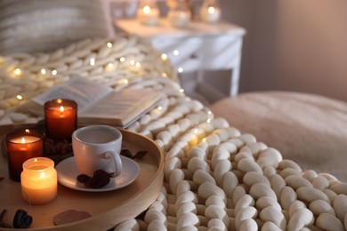 Photo of Burning candles, lights, coffee and decor on bed indoors. Autumn atmosphere