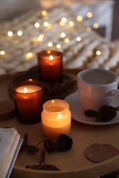 Photo of Burning candles, lights, coffee and decor on bed indoors, closeup. Autumn atmosphere