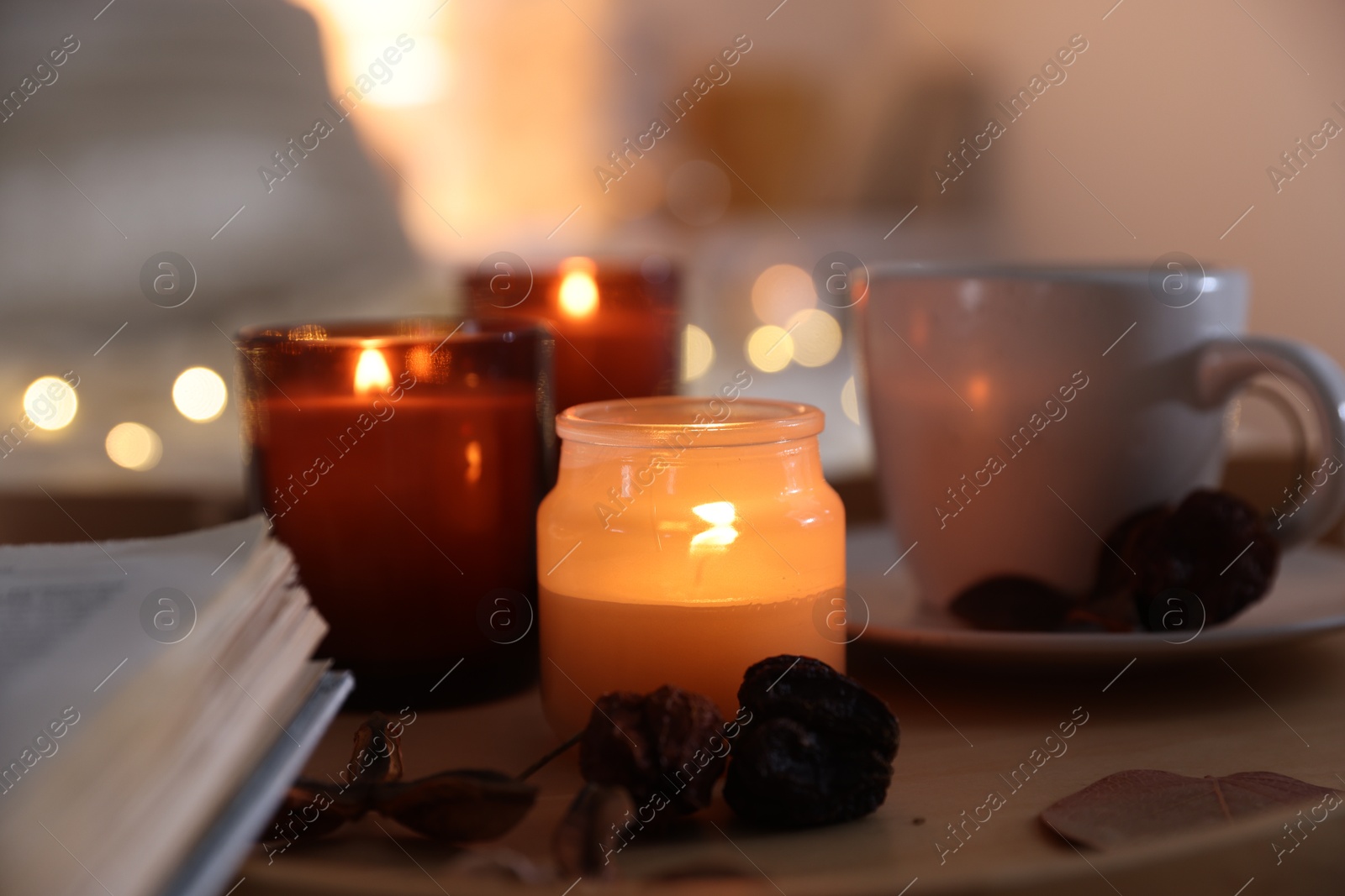 Photo of Burning candles, cup of drink and decor on tray indoors, closeup. Autumn atmosphere