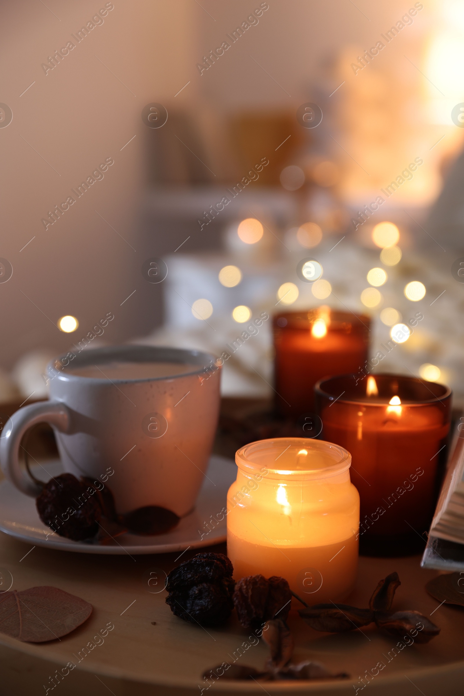 Photo of Burning candles, coffee and decor on tray indoors, closeup. Autumn atmosphere