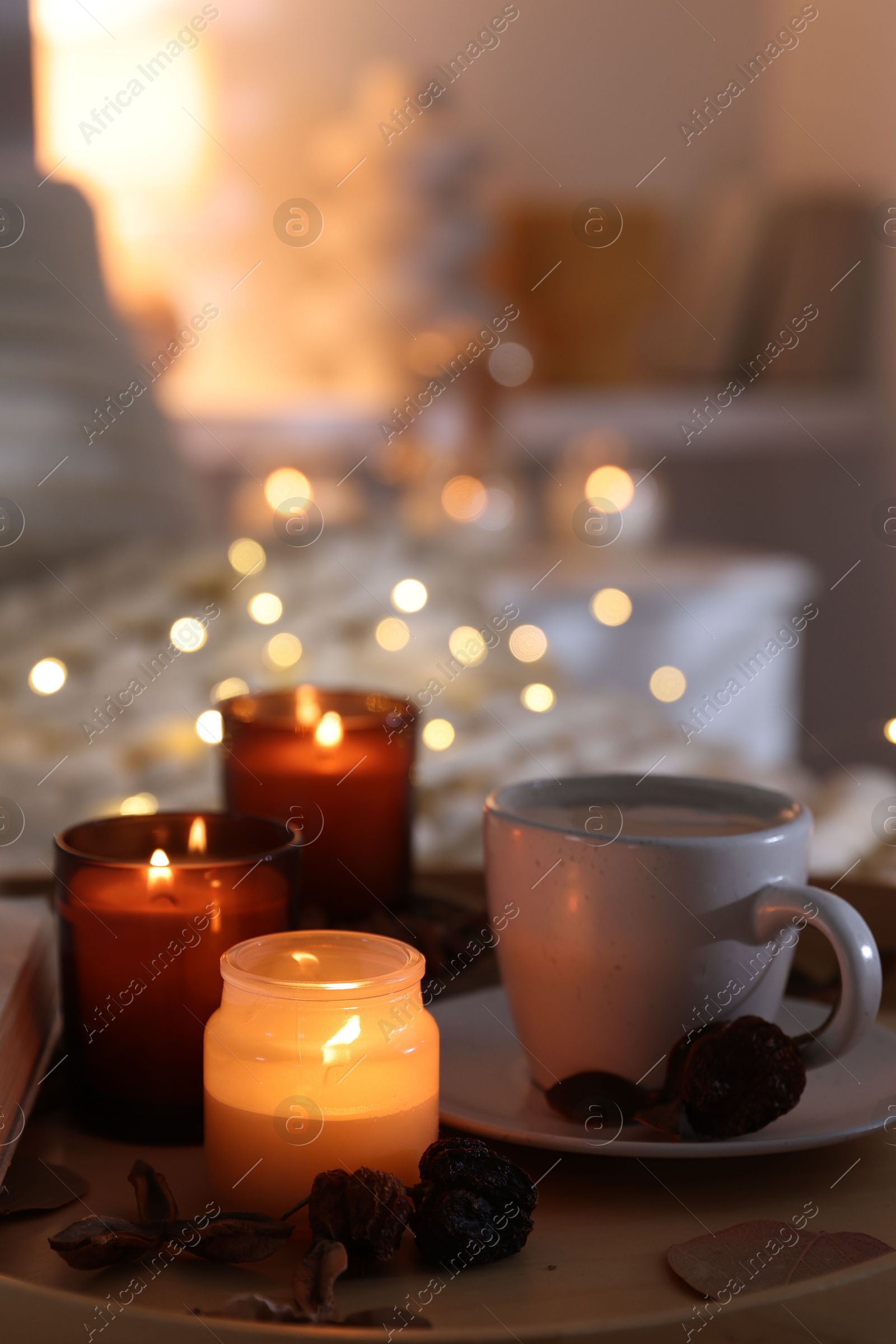 Photo of Burning candles, lights, coffee and decor on bed indoors, closeup. Autumn atmosphere