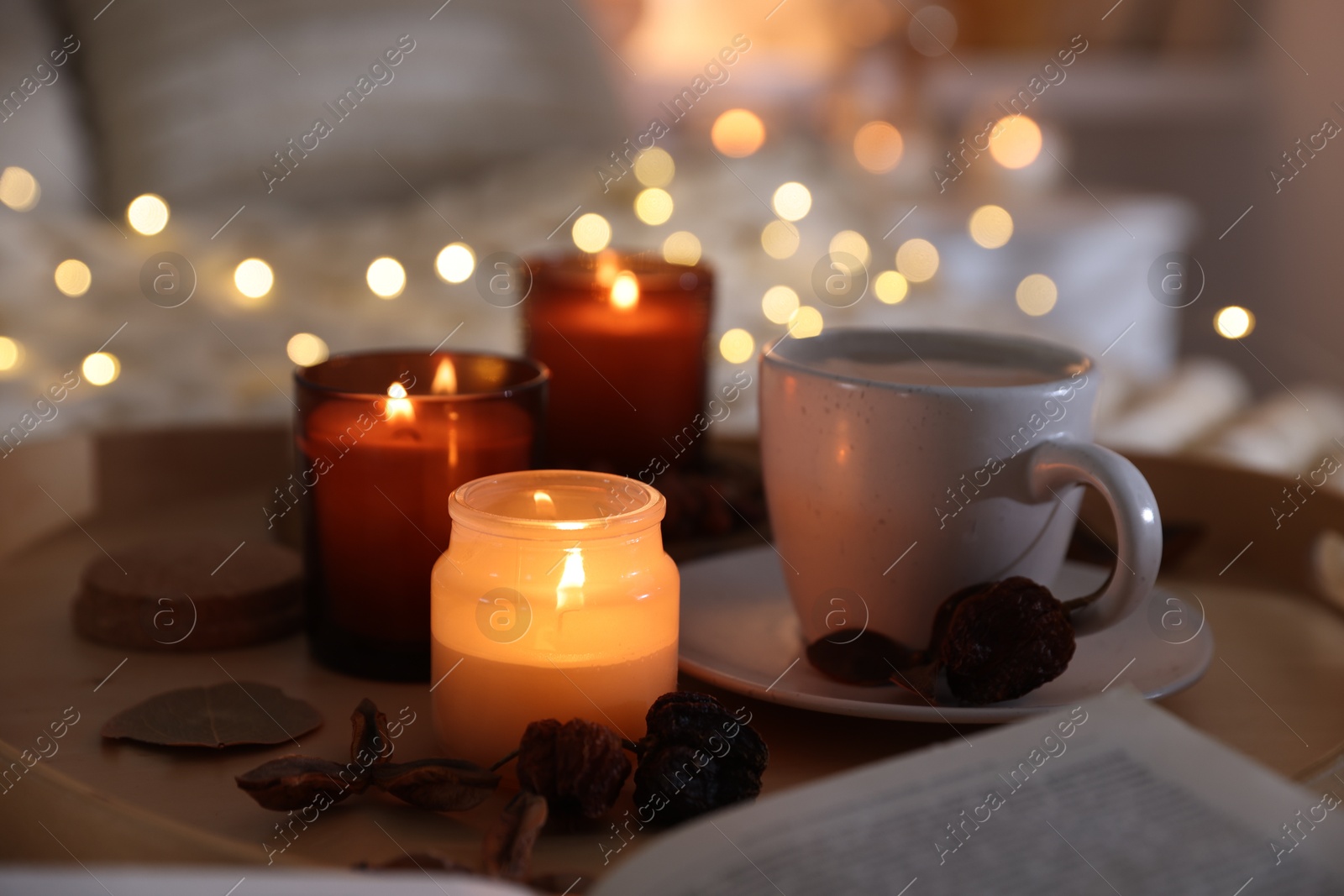 Photo of Burning candles, lights, coffee and decor on bed indoors, closeup. Autumn atmosphere