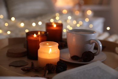 Photo of Burning candles, lights, coffee and decor on bed indoors, closeup. Autumn atmosphere