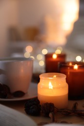 Photo of Burning candles, cup of drink and decor on tray indoors, closeup. Autumn atmosphere