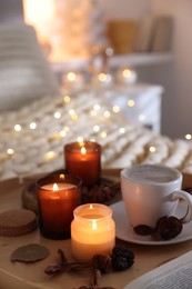 Photo of Burning candles, lights, coffee and decor on bed indoors. Autumn atmosphere