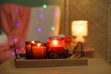 Photo of Burning candles and autumn decor on wooden table indoors