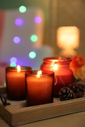 Photo of Burning candles and autumn decor on wooden table indoors, closeup