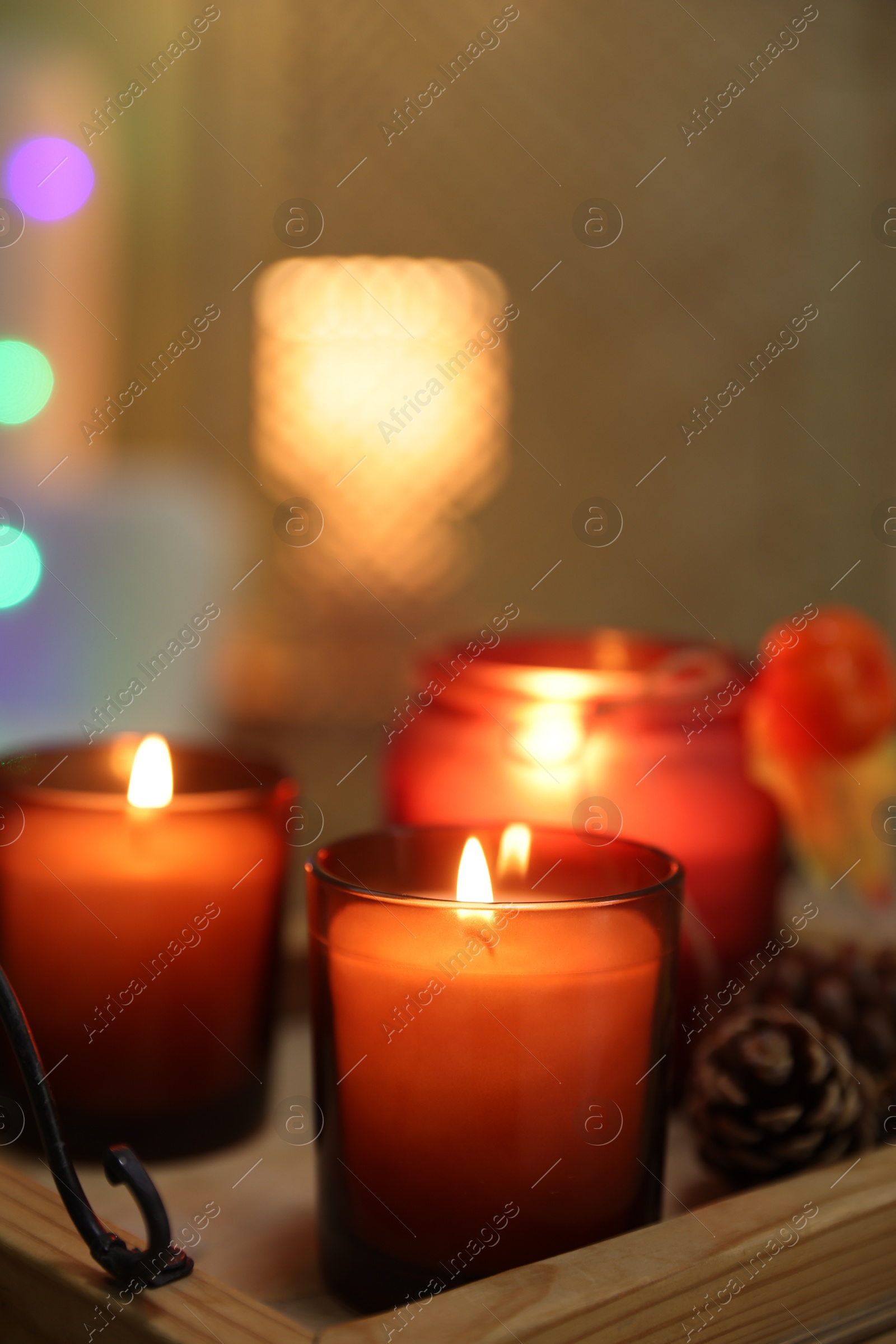 Photo of Burning candles and cone on tray indoors, closeup. Autumn atmosphere