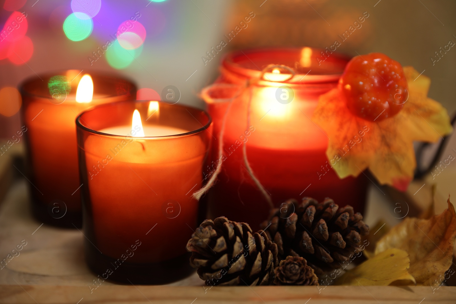 Photo of Burning candles and autumn decor on tray, closeup