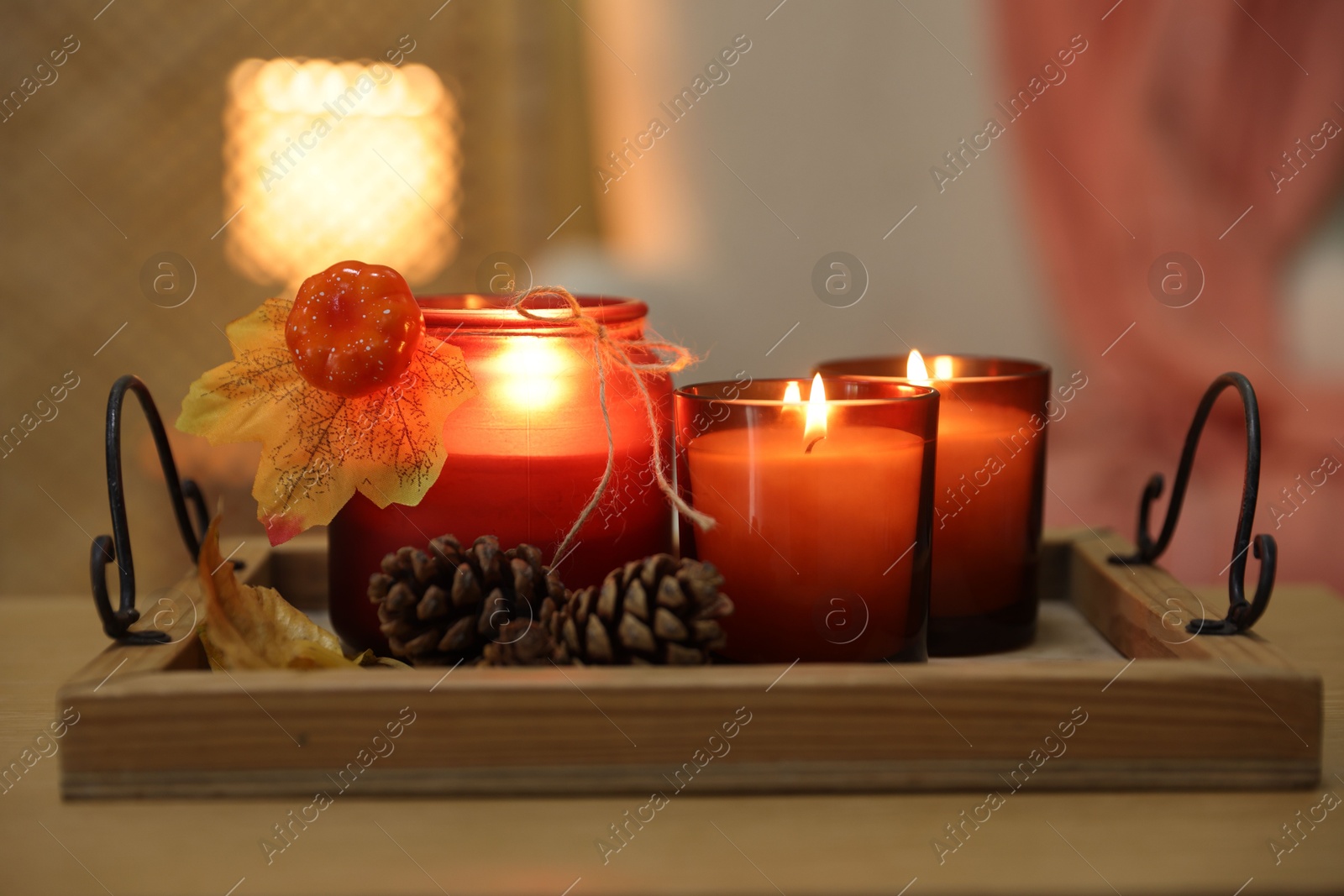 Photo of Burning candles and autumn decor on table indoors